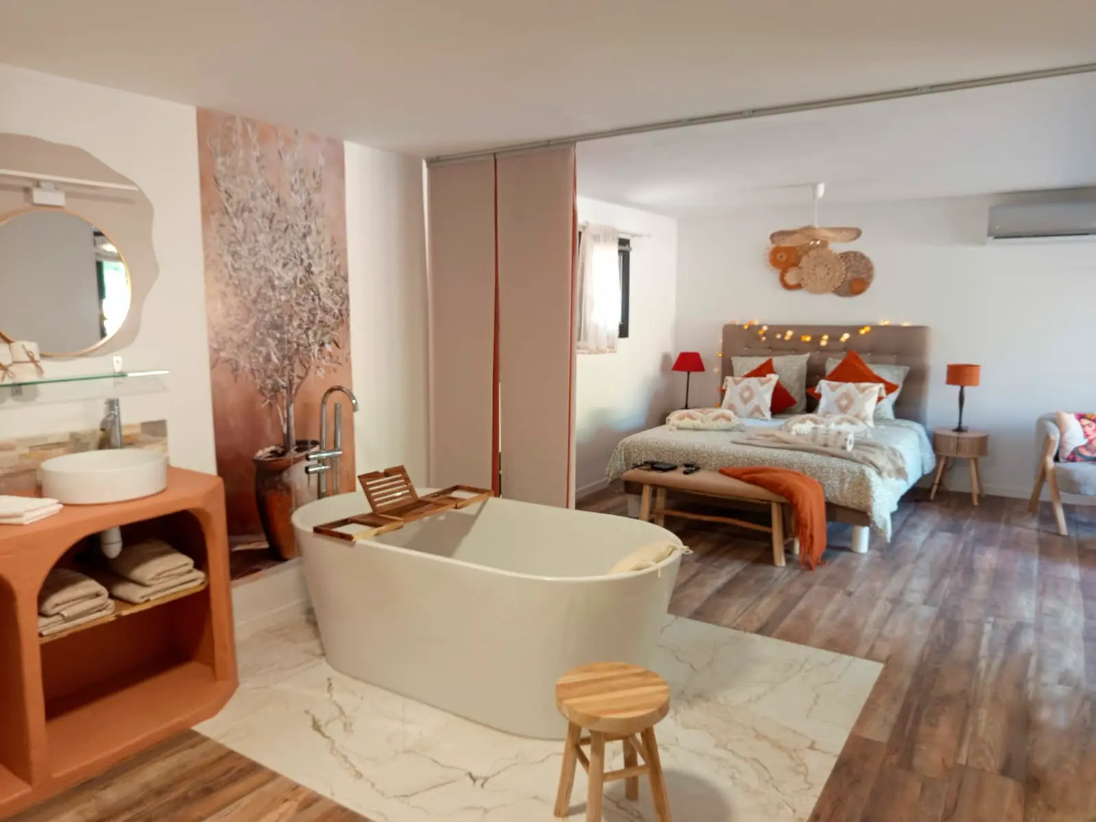 Vue d'ensemble de la suite avec baignoire, vasque terracotta et coin nuit